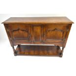 A reproduction oak sideboard of small proportions with two panelled doors raised on block feet,