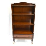 A reproduction mahogany waterfall bookcase with single base drawer terminating on brass castors,