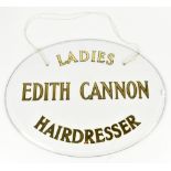 A glass advertising sign with applied gilt lettering 'Edith Cannon Ladies Hairdressers', 46 x 61cm.