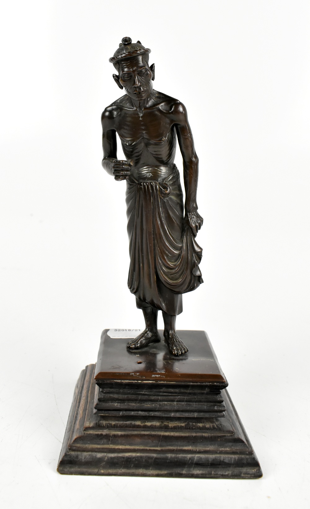 A Japanese Meiji period bronze figure of an ascetic monk on stained stepped wooden base, height 21.