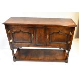 A reproduction oak dresser base with moulded rectangular top above twin fielded panelled doors on