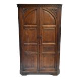 A reproduction carved oak hall robe with twin panelled doors, height 183cm, width 109cm, depth