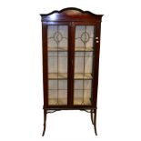 An Edwardian mahogany twin door display cabinet, the two doors with lead glazed panels, raised on