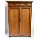 A 19th century architectural oak wardrobe with twin panelled doors enclosing hanging compartments