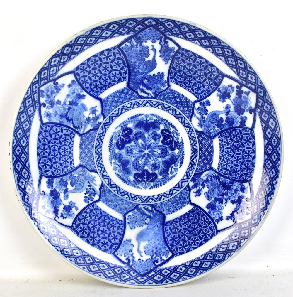 A large Japanese Meiji period blue and white charger decorated with peacocks and geese within floral