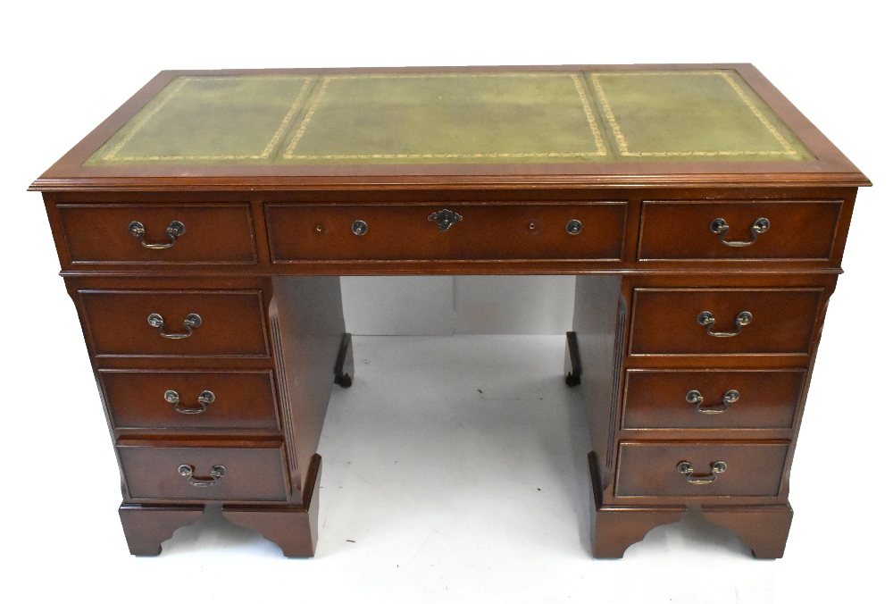 A reproduction mahogany veneered knee hole desk with leather inset top above an arrangement of six