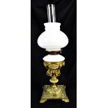 An early 20th century brass oil lamp with embossed Arts & Crafts style decoration, with milk glass