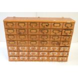 A vintage pine multi bank of forty-two short drawers each with brass clips for labelling and