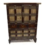 A Chinese hardwood 'chicken coop' cabinet with pierced panels and foliate detailed metal mounts,