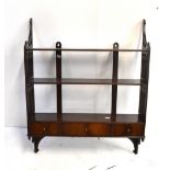 A 19th century set of mahogany wall hanging shelves with pierced detail and three drawers to lower