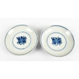 A pair of Chinese porcelain shallow footed bowls painted with blue and white symbols and stylised