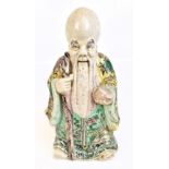 An early 19th century Chinese earthenware figure of Shou Lao holding peach and staff with