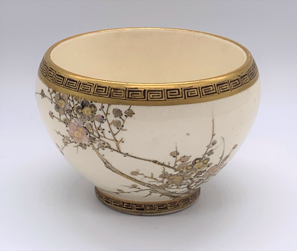 A Japanese Meiji period Satsuma bowl with twin Greek key borders and cream ground body decorated