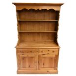 A modern pine dresser with plate rack back, the upper section with two fixed shelves above two