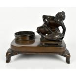 A Japanese Meiji period bronze inkstand featuring a figure holding a knife before a carp and inkwell