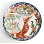 A Japanese Meiji period Imari wall charger painted with figures in landscape setting, diameter
