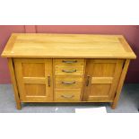 A modern oak sideboard with twin cupboard doors flanking a central column of four drawers, 130 x
