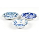 Three Chinese blue and white floral decorated saucer dishes, the larger two unmarked, the smallest