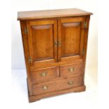 A reproduction oak side cabinet with twin panelled cupboard doors above two short and one long