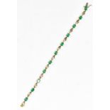 A yellow metal emerald and diamond bracelet, stamped 14k, set with eleven emeralds, approx 9.4g,