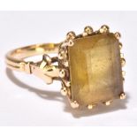 A yellow metal dress ring set with emerald cut pale yellow coloured stone, size R, rubbed mark