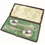 CW FLETCHER; a cased pair of Edward VII hallmarked silver preserve spoons with bright cut detail,