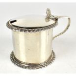 A George III hallmarked silver mustard pot of drum form with scallop moulded thumb piece and