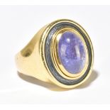 DE VROOMEN; an 18ct yellow gold oval cut tanzanite and grey guilloché enamel decorated ring, size