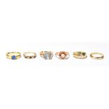 A group of six yellow metal rings including a sapphire example, wedding band, a large blue stone,