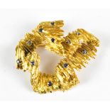 An 18ct yellow gold and saphhire textured brooch, with eleven applied sapphires, approx 22.7g.