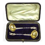 A cased pair of Continental unmarked white metal sifting spoons with figural finials and further