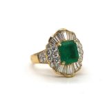 A yellow metal emerald and diamond ring, the central emerald weighing approx 2cts within a border of