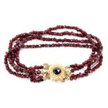 A yellow metal and garnet coloured bead bracelet with floral decorated clasp.Additional