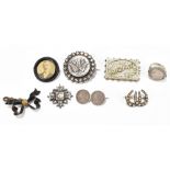 A Victorian white metal brooch of circular form with floral detail, and three further brooches, a