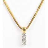 A 9ct yellow gold chain suspending an 18ct yellow and white gold three stone diamond pendant, length