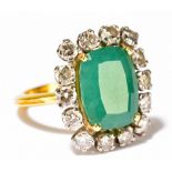 An unmarked yellow metal emerald and diamond cluster ring, the central rounded rectangular emerald