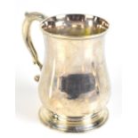 A George II hallmarked silver mug of baluster form with spreading circular foot and double scroll