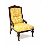 A Victorian mahogany fireside chair with carved decoration upholstered in a mustard damask-type