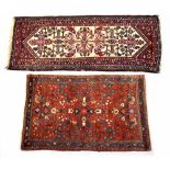 An Iranian wool rug with floral motifs on a red ground within stepped multi-borders in blue, pink,