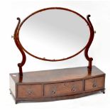 A 19th century mahogany toilet mirror with oval plate, on a pair of scroll supports,