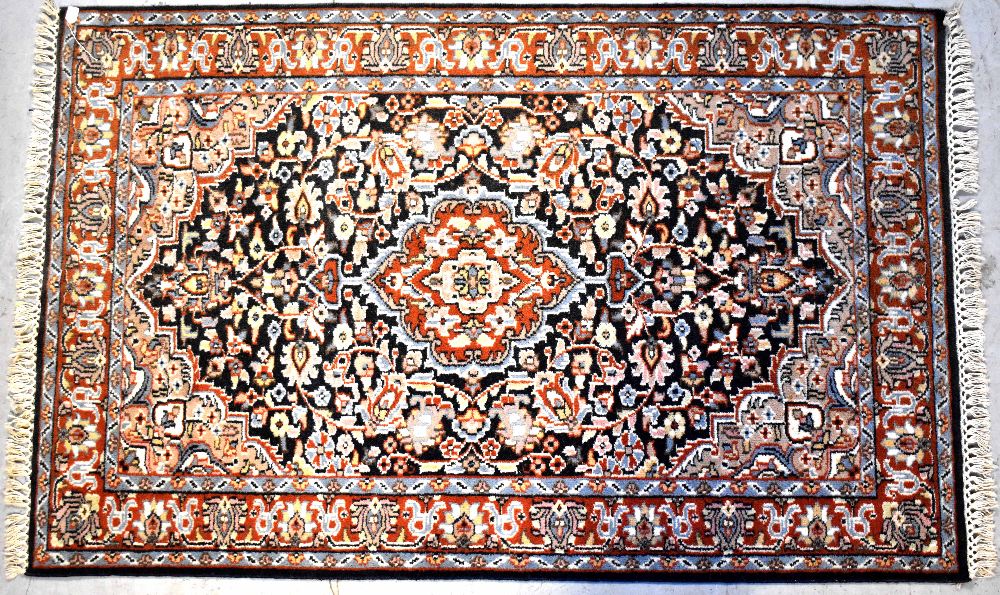 A Persian wool rug with central medallion with floral and scroll motifs within stepped