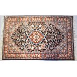 A Persian wool rug with central medallion with floral and scroll motifs within stepped