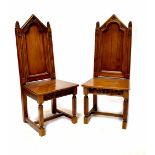 A pair of Gothic Revival oak dining chairs with ecclesiastical-style arched backs and carved finial