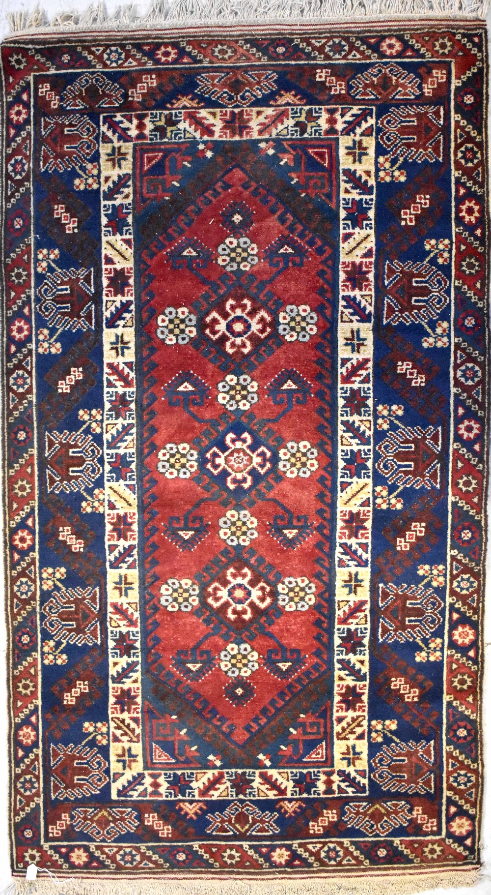 An Eastern woollen rug with central panel of stylised floral medallions within stepped