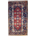 An Eastern woollen rug with central panel of stylised floral medallions within stepped