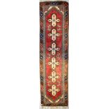 An Eastern woollen rug with three stylised floral medallions, on a central panel with red ground,