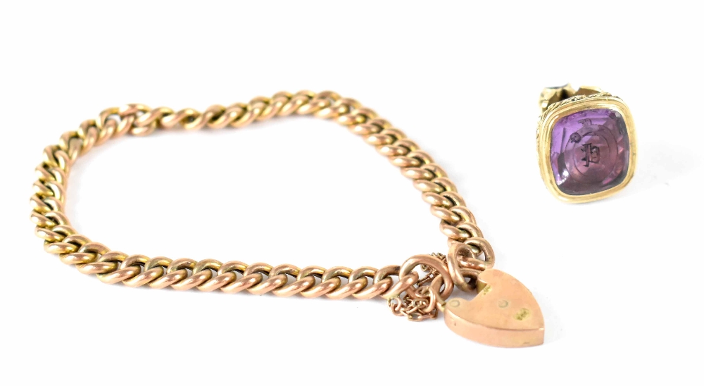 A yellow metal link bracelet with a 9ct gold padlock clasp and a yellow metal fob with amethyst