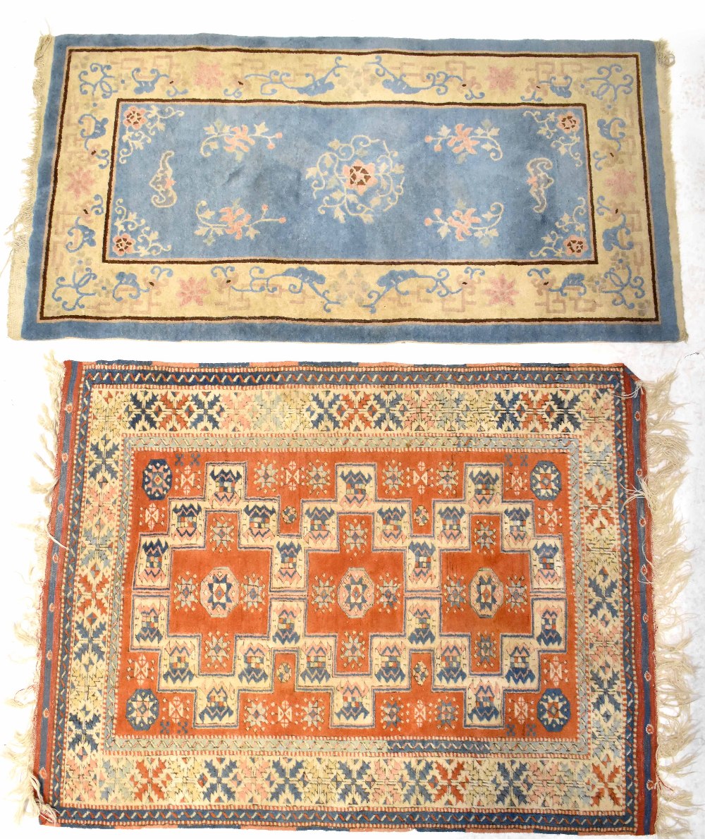 A Turkish hand knotted wool rug with geometric motifs and stylised flowers on a red ground,