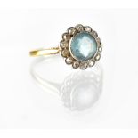 An 18ct gold ring set with pale blue stone and surrounded with fifteen tiny old-cut diamonds set in