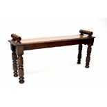 A carved oak window seat with turned handles and carved decoration on turned legs,